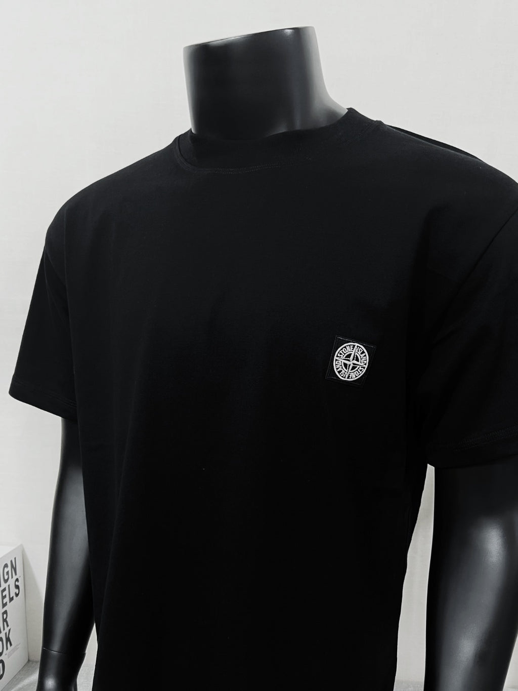 Black short-sleeve T-shirt with crew neck and small chest logo patch