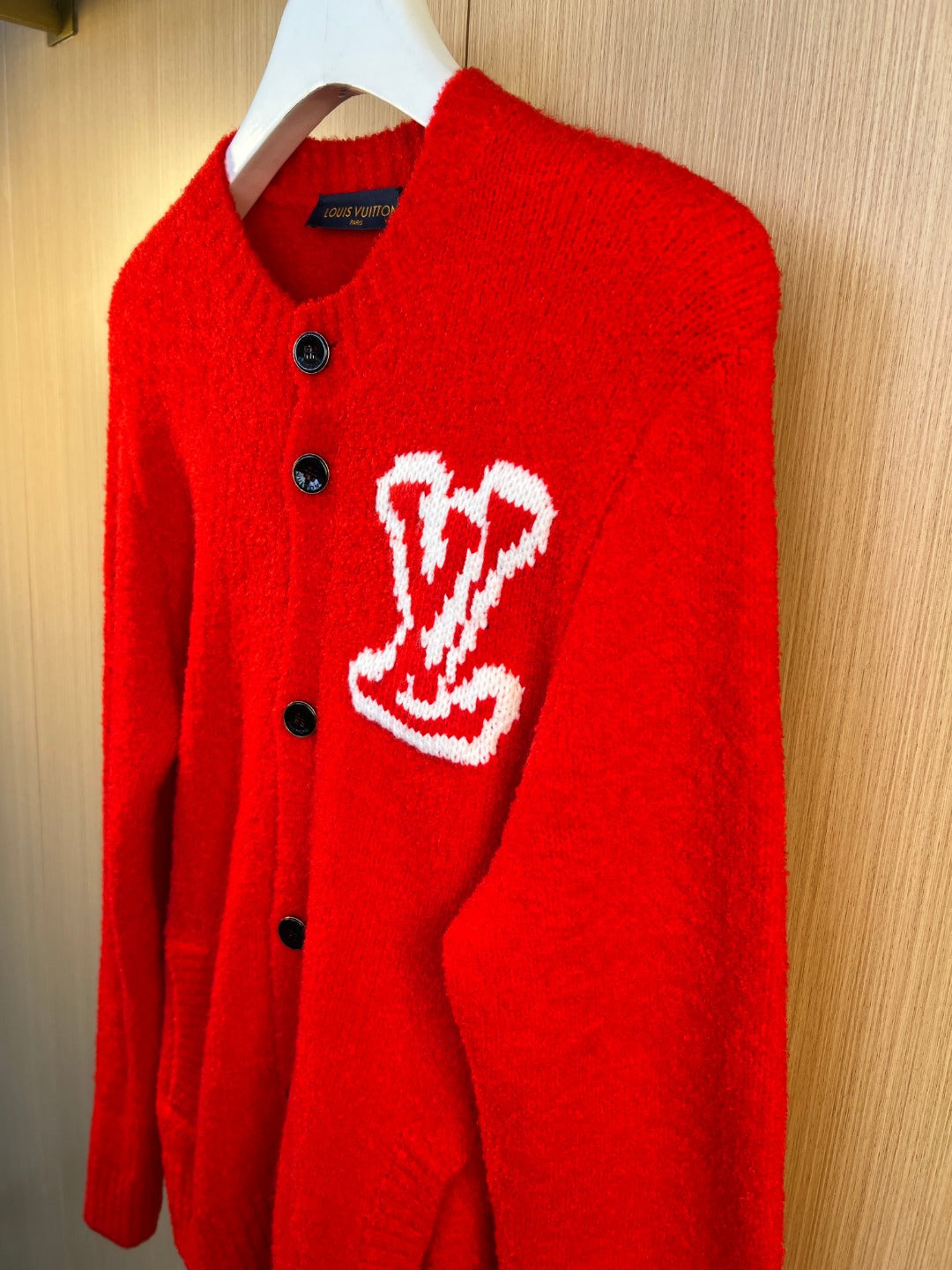 Red knit cardigan with white heart logo and black button front