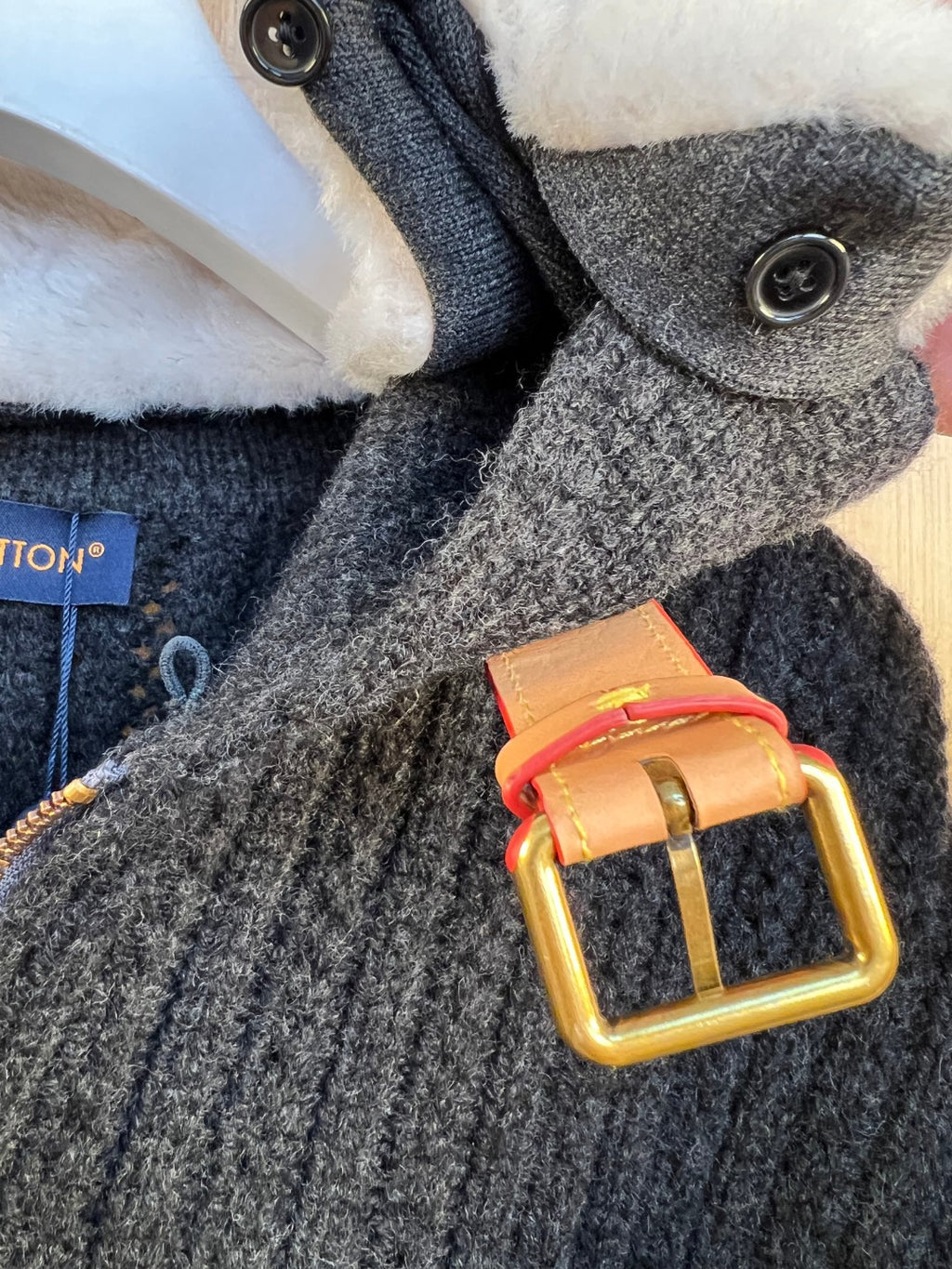 Gray knit sleeve cuff with snap button and orange-and-gold belt detail