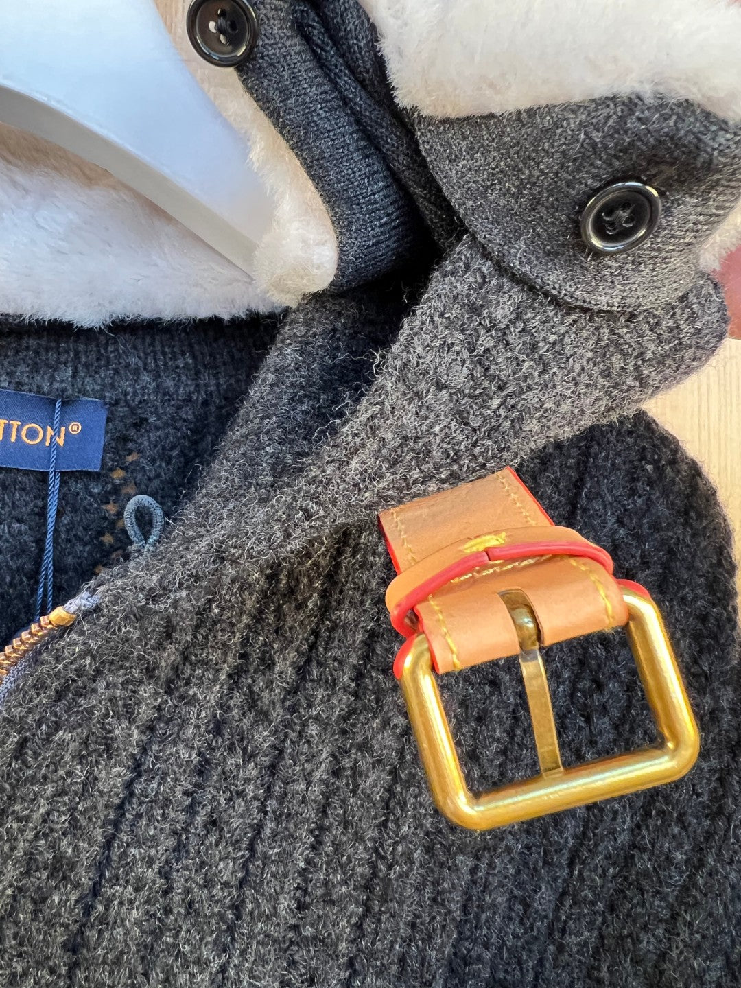 Gray knit sleeve cuff with snap button and orange-and-gold belt detail