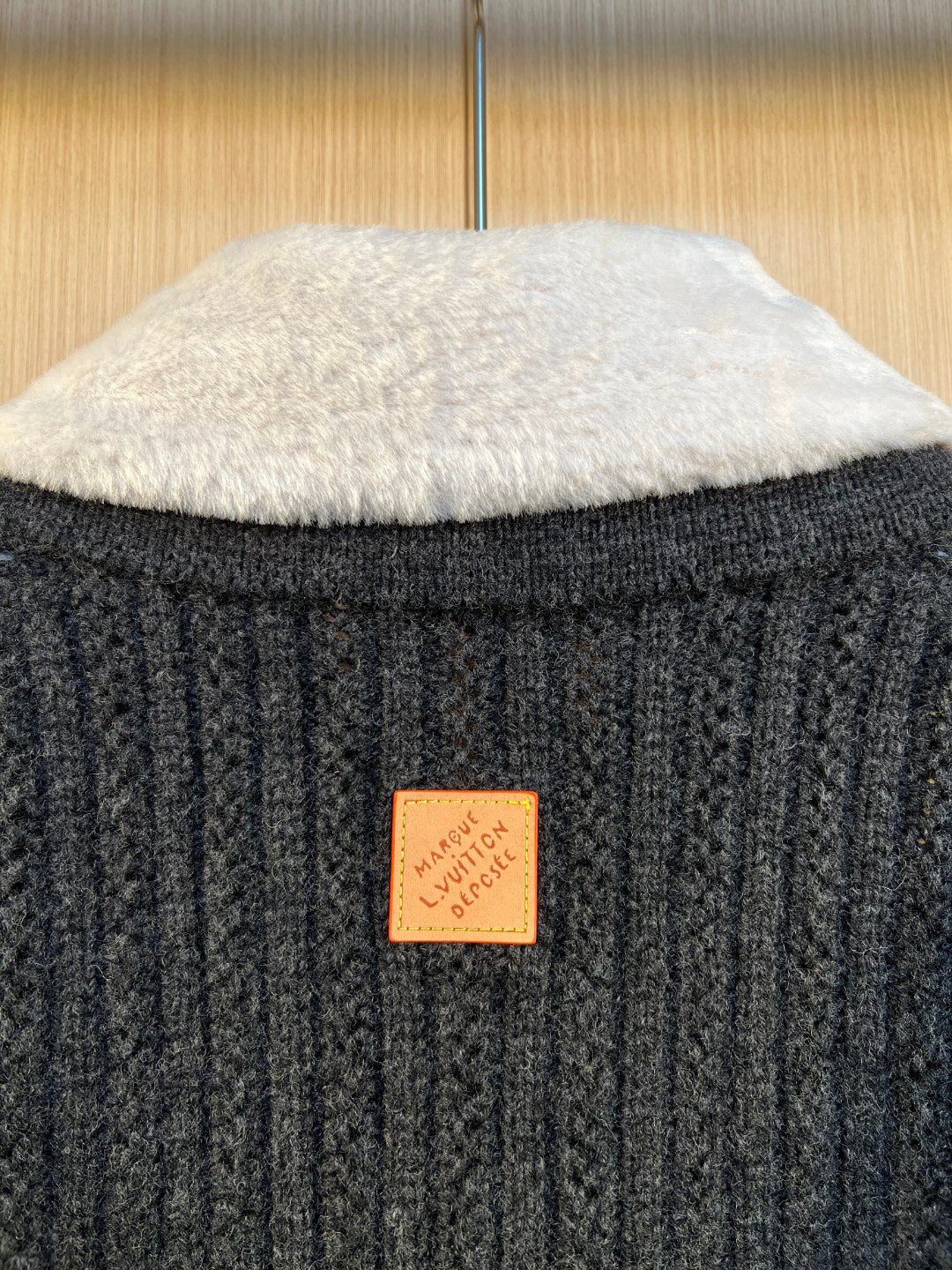 Orange Louis Vuitton patch on dark knit back near the neckline