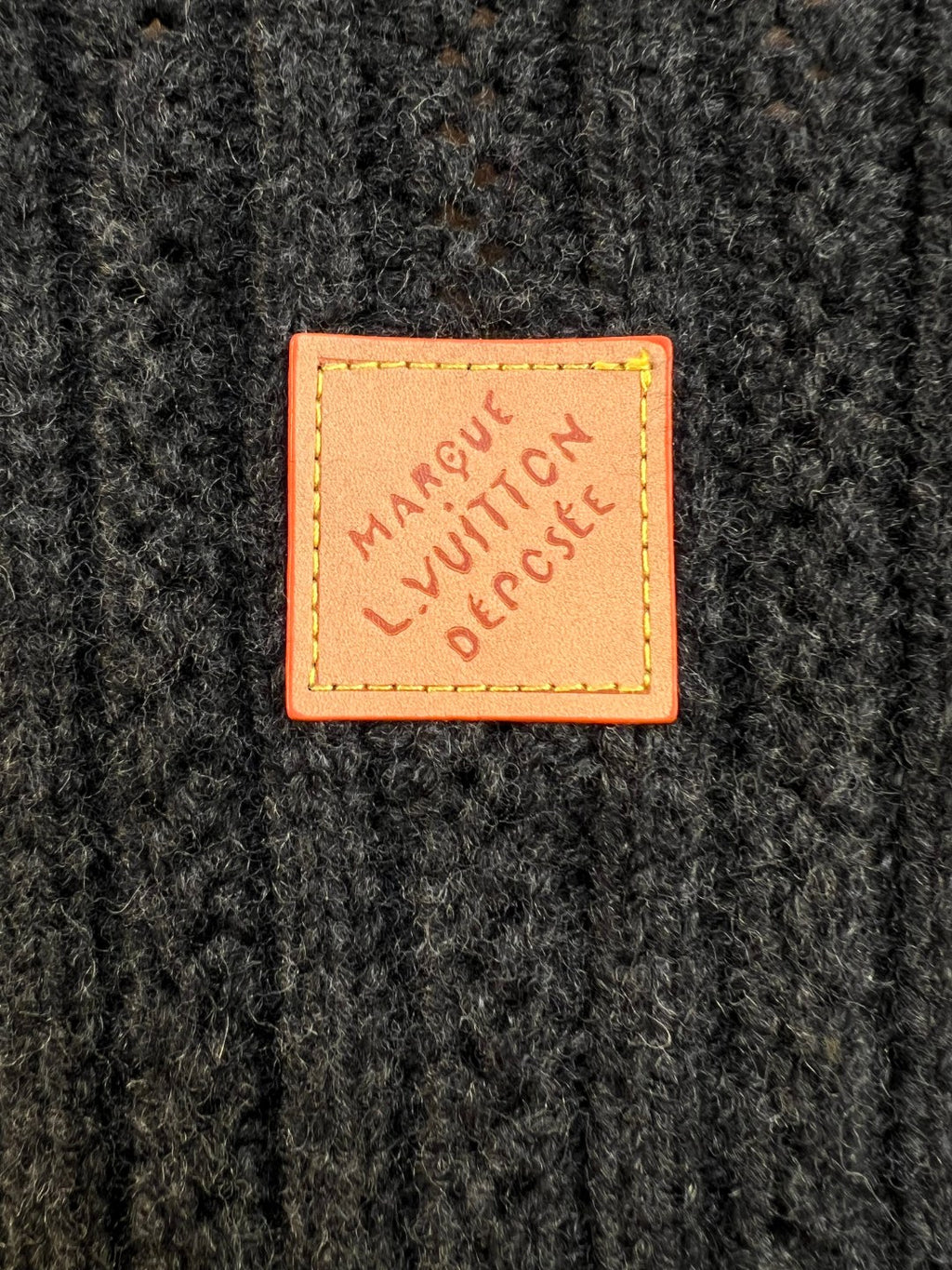 Orange Louis Vuitton patch on dark knit fabric reading 'MAKE LOVE, RESPECT'