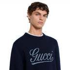 Gucci dark blue crewneck sweater with script logo at chest, model close-up
