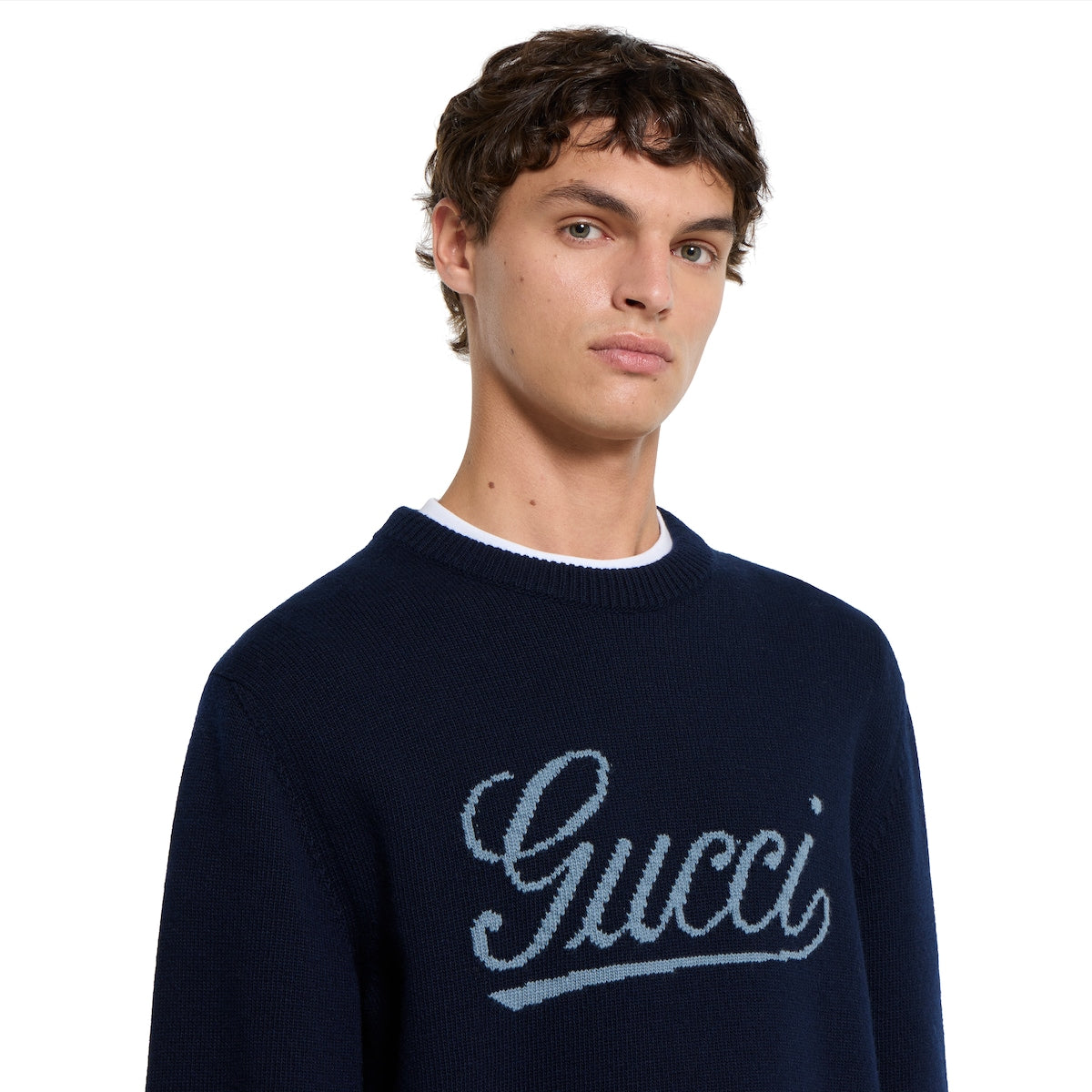 Gucci dark blue crewneck sweater with script logo at chest, model close-up