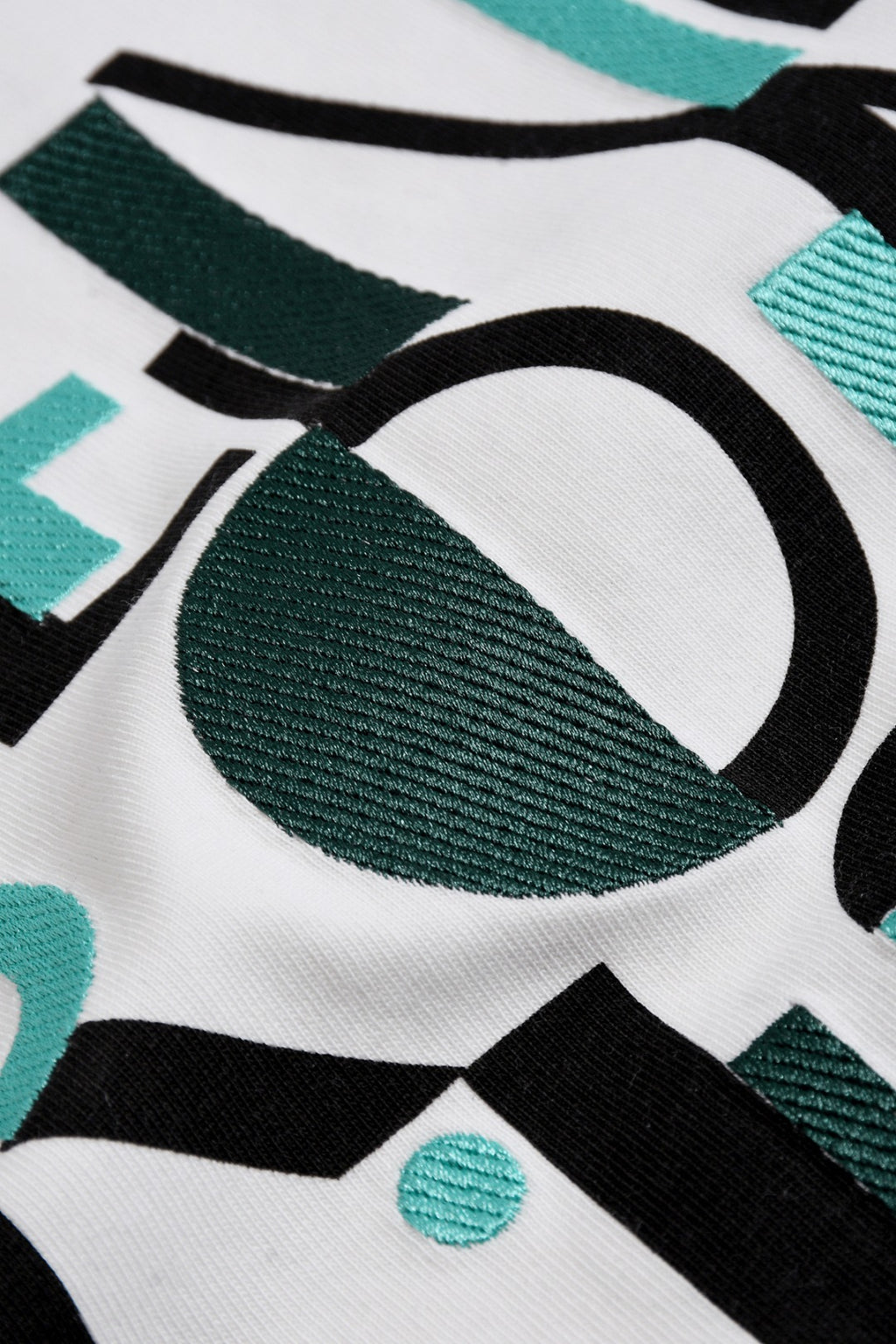 White Fendi T-shirt fabric close-up with teal and black Roma 1975 print