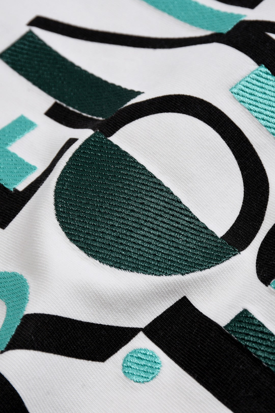 White Fendi T-shirt fabric close-up with teal and black Roma 1975 print