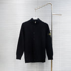 Black knit button-up jacket with high collar on hanger