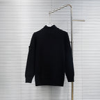 Black knit jacket back view with high collar on hanger