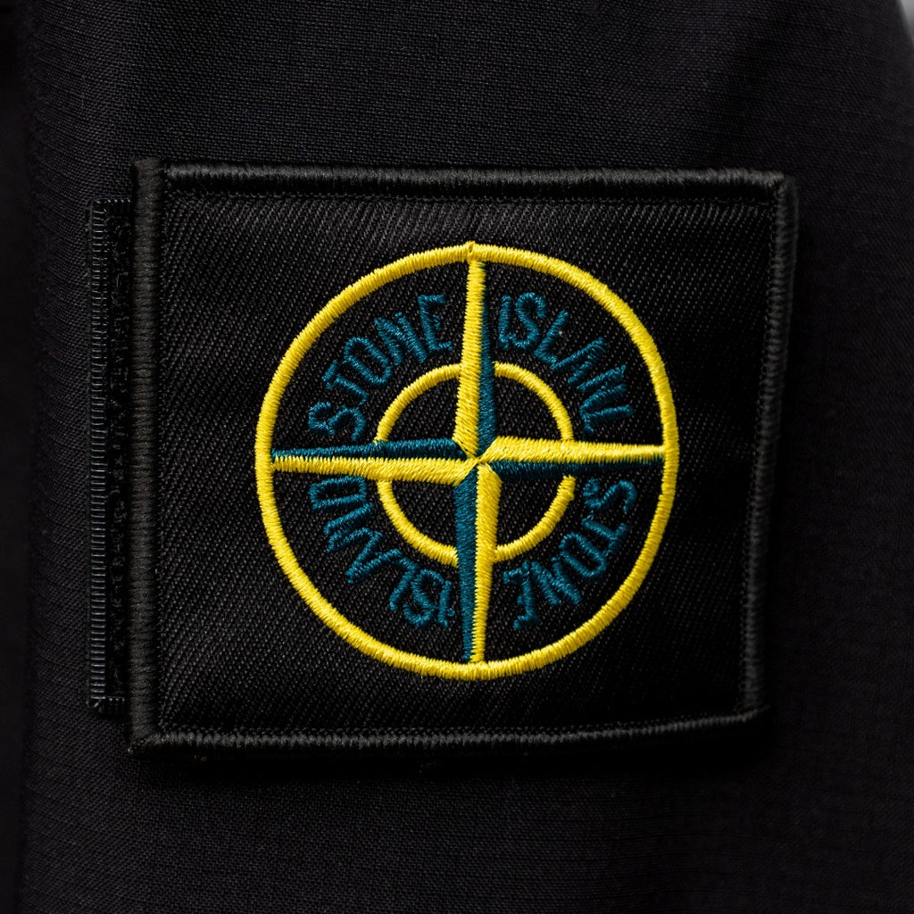 Stone Island embroidered circular logo patch on dark jacket fabric