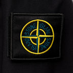 Stone Island embroidered circular logo patch on dark jacket fabric