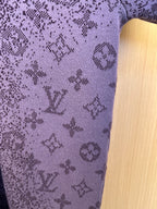 Louis Vuitton knit fabric detail with light monogram symbols on dark purple background
