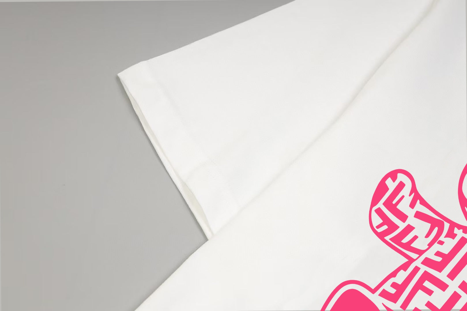 White T-shirt sleeve with partial pink bear graphic