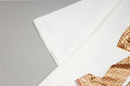 White T-shirt fabric close-up with part of the monogram bow
