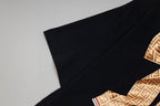 Black short-sleeve shirt sleeve detail with part of gold monogram bow
