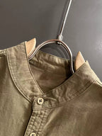 Long-sleeve shirt neckline close-up with front buttons, olive-brown canvas.