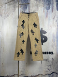 Tan cargo-style pants with black embroidered cross motifs, front view.