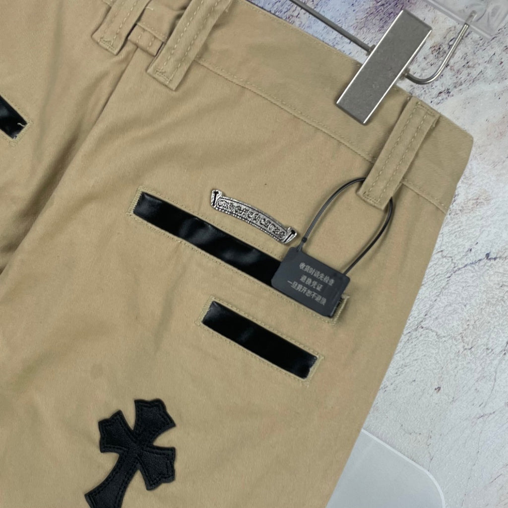 Tan pants with black applique details and waistband labels, close-up back view.