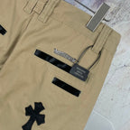 Tan pants with black applique details and waistband labels, close-up back view.