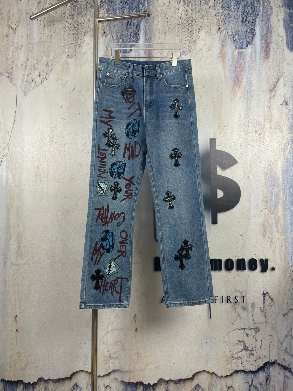 Light blue denim pants with black cross appliques and colorful graphic print on front