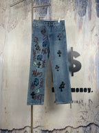 Light blue denim pants with black cross appliques and colorful graphic print on front