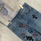 Light blue denim pants with curved waistband and multicolor front graphic print