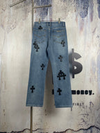 Light blue denim pants with black cross appliques and scattered front graphics