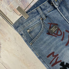 Light blue denim pants close-up of button fly and multicolor front graphic print