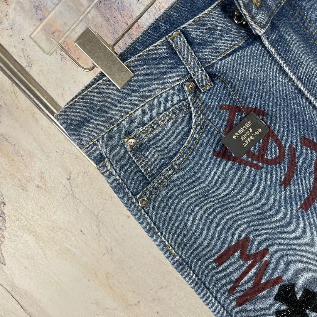 Light blue denim pants close-up of button fly and multicolor front graphic print