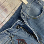 Light blue denim pants close-up of button fly, stitching, and black zipper pull