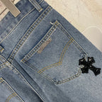 Light blue denim pants close-up of back pocket with small patch and black applique