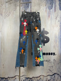 Dark denim pants with colorful cross patches and frayed hems
