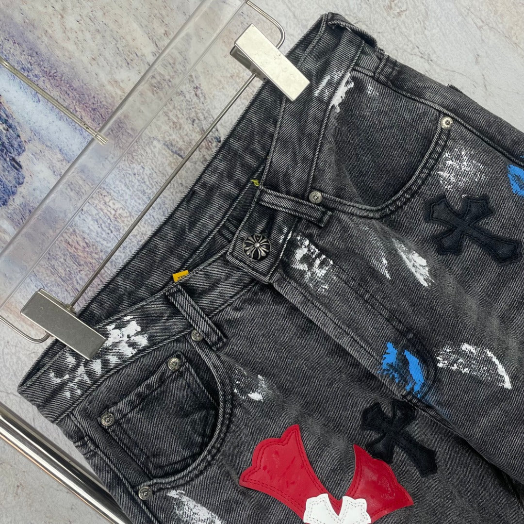 Dark denim pants close-up with distressing and colorful cross appliques