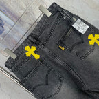 Dark denim pants with yellow cross patches, stitched pockets, and waistband