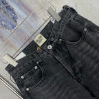 Dark gray denim pants close-up of waistband, button fly and cross detailing