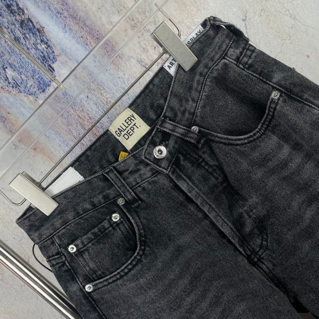 Dark gray denim pants close-up of waistband, button fly and cross detailing