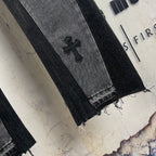 Dark gray denim pants hem with frayed edge and embroidered cross patch