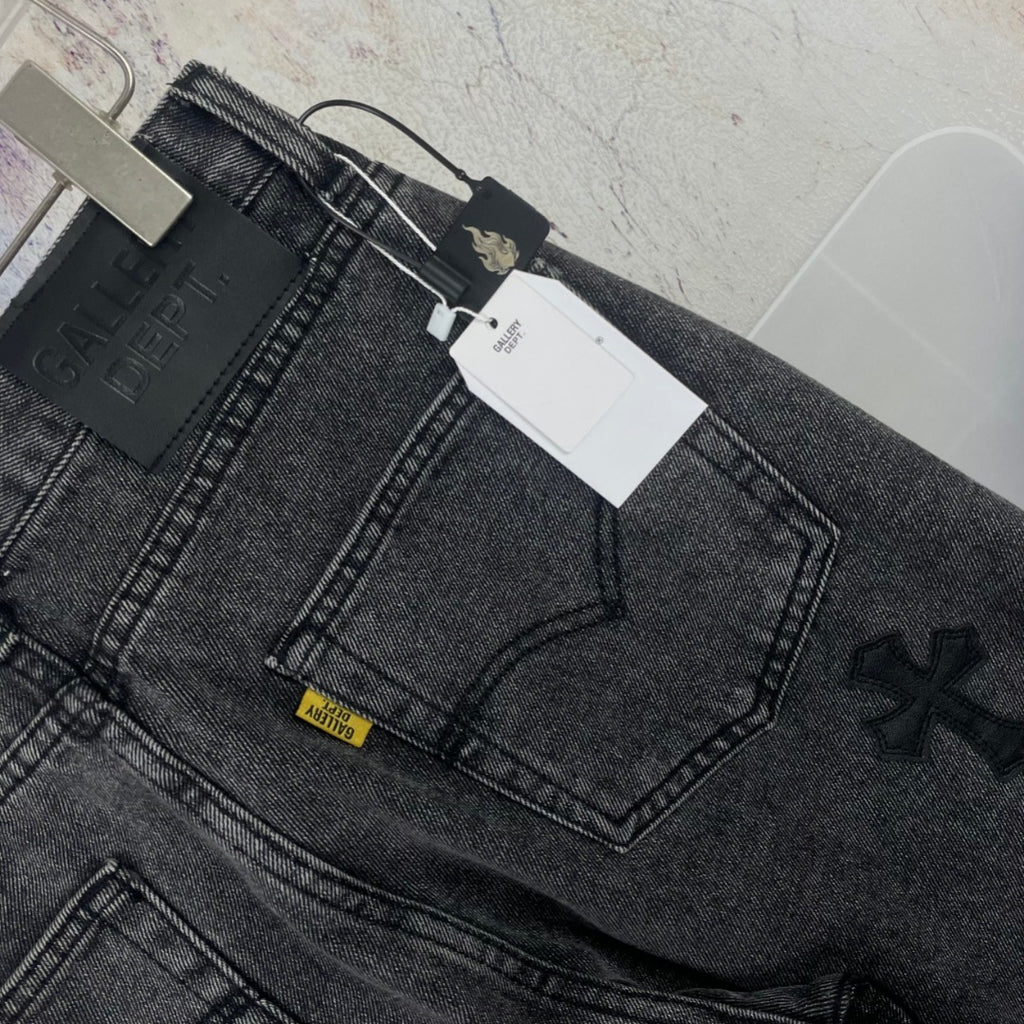 Dark gray denim pants close-up of waistband and embroidered cross detail