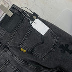 Dark gray denim pants close-up of waistband and embroidered cross detail