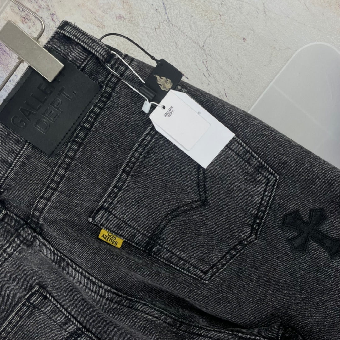 Dark gray denim pants close-up of waistband and embroidered cross detail
