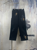 Black pants with wide legs and gold cross embroidery on the front