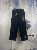 Black pants with wide legs and gold cross embroidery on the front