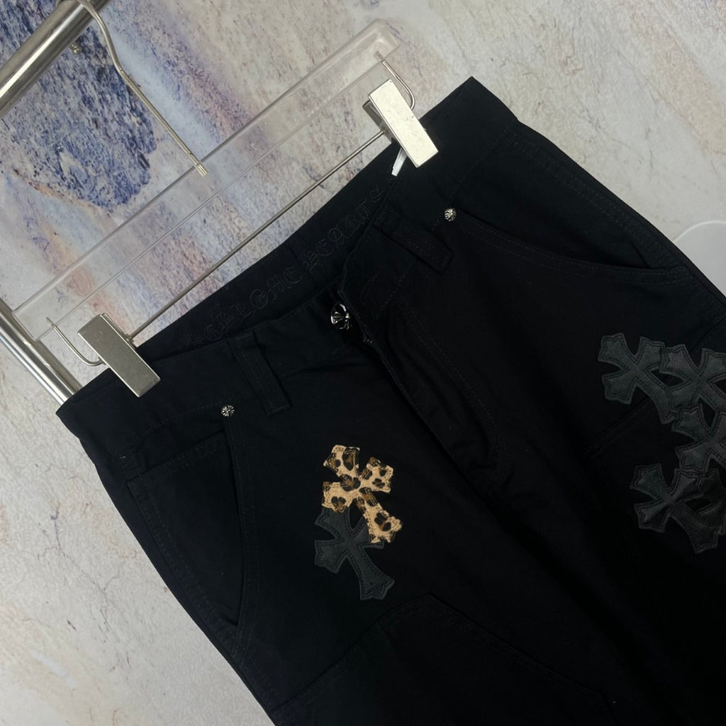 Black pants close-up showing gold and dark star/cross appliques on the leg