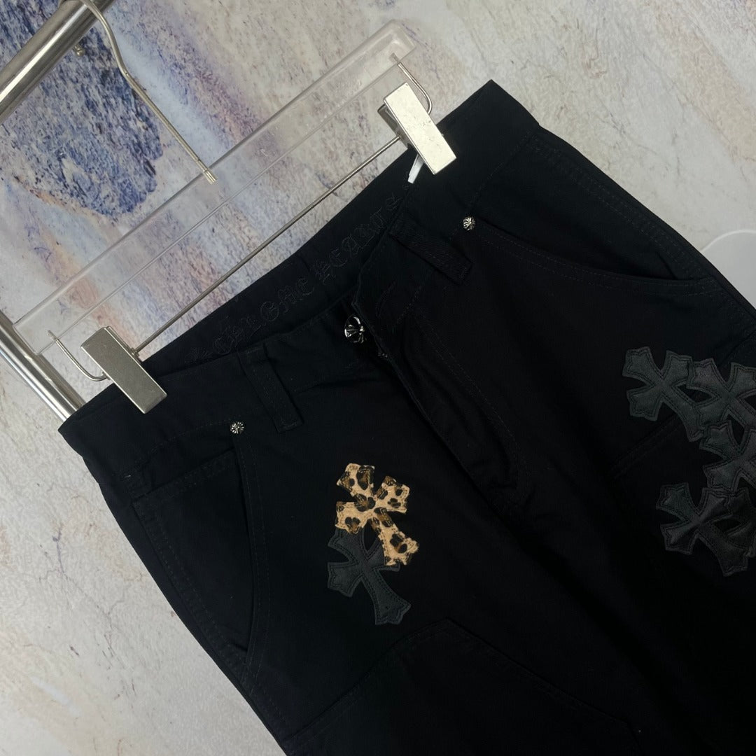 Black pants close-up showing gold and dark star/cross appliques on the leg