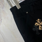 Black pants with side pocket and gold cross applique near the hem