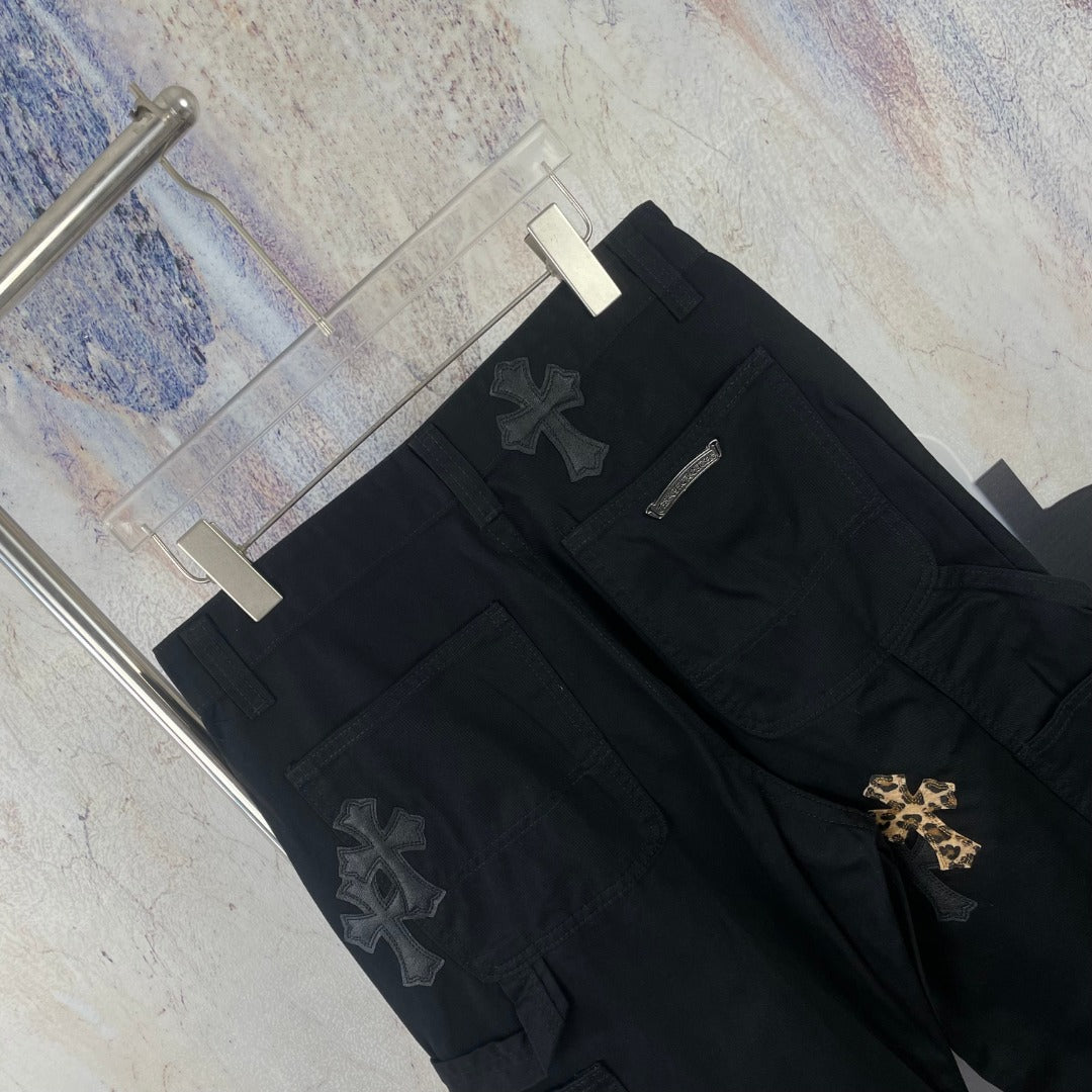 Black wide-leg pants with multiple cross patches and a front zipper placket