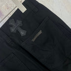 Black pants front close-up with cross patches and a zip fly