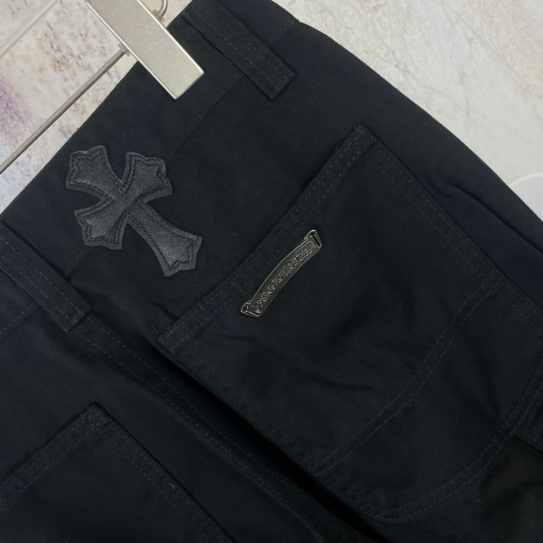 Black pants front close-up with cross patches and a zip fly