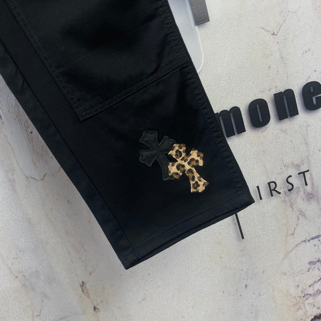 Black pants with V-shaped pocket stitching and gold cross patch on the leg