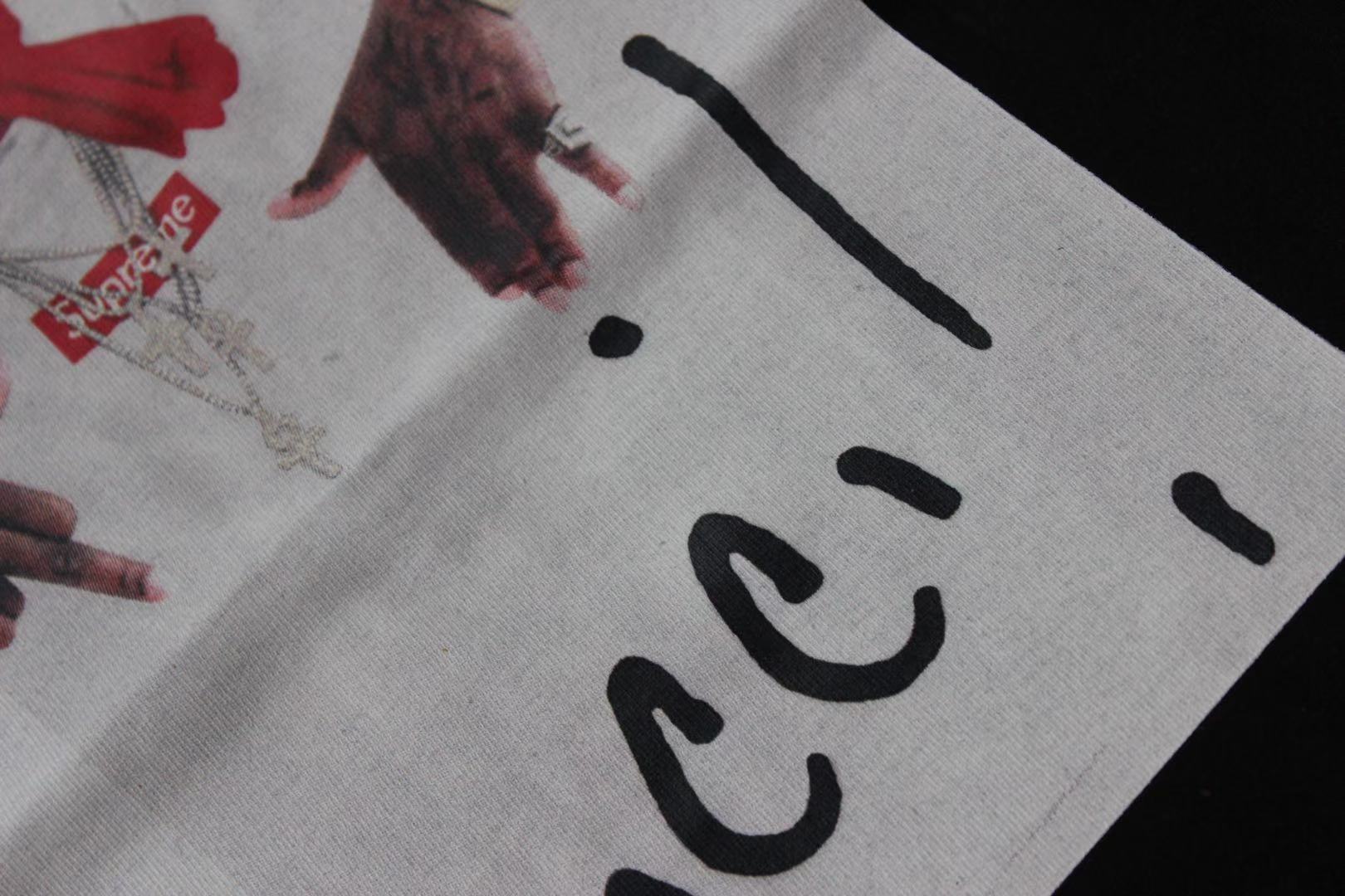Stussy T-shirt print close-up showing black 'Gucci' lettering and hands