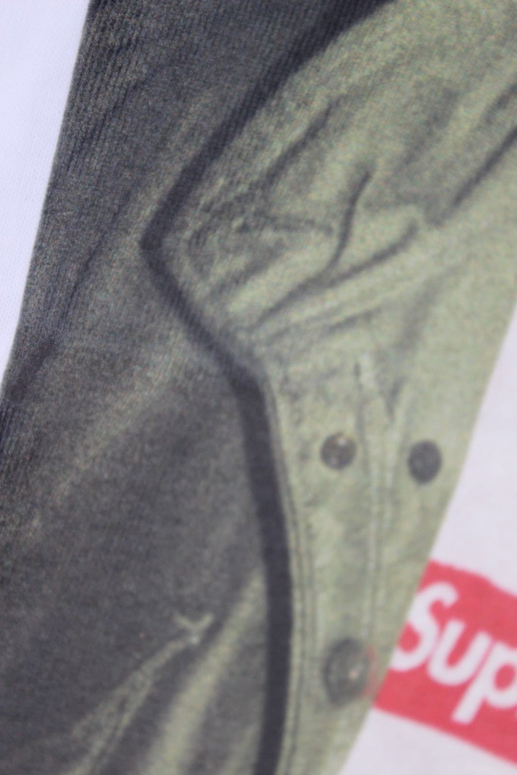 Graphic T-shirt print detail: green jacket fabric with red Supreme band edge